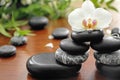 Spa stones with beautiful orchid flower on wooden table Royalty Free Stock Photo
