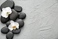 Spa stones and beautiful orchid flowers on grey textured background Royalty Free Stock Photo