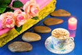 Spa stones, beautiful roses, candle and coffee. Hot stone massage-stone therapy, effective treatment for many diseases. On a blue
