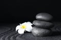 Spa stones and plumeria flower on black sand with pattern, space for text. Zen concept Royalty Free Stock Photo