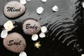 Spa stones with words Mind, Body, Soul and rose petals in water. Zen lifestyle