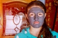 Spa teen girl applying facial clay mask. Beauty treatments. Over blue background. Royalty Free Stock Photo