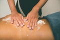 Spa therapist applying scrub salt and cream on young woman back at salon spa. Hands massaging female back with scrub Royalty Free Stock Photo