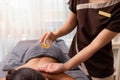 Spa therapist applying treatment oil on young woman back at salon spa Royalty Free Stock Photo
