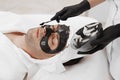 Spa therapy for men receiving facial black mask. Royalty Free Stock Photo