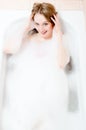 Spa time: closeup portrait of blue eyes beautiful blond young lady having fun relaxing in bath happy smile over soap water Royalty Free Stock Photo