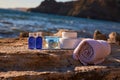 Spa treatment and relax near sea. Bottles with aroma oils and glass candles on rock. Towel and containers with cream. Royalty Free Stock Photo