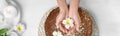 Spa treatment. Woman soaking her hands in bowl with water and flowers on white wooden table, top view. Banner design Royalty Free Stock Photo