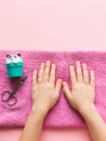 Spa treatments for hand skin and nails for children. Young girl`s hands are on pink soft towel. Beauty and care concept. Royalty Free Stock Photo