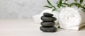 Spa and wellness center - stack of massage stones and towels with green plant on white wooden table. banner Royalty Free Stock Photo