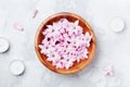 Spa and wellness composition of perfumed pink flowers water in wooden bowl and candles on gray stone table. Aromatherapy.