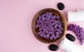 Spa and wellness concept with lilac flowers in water in a wooden bowl and towel aromatherapy and black stones, top view, flat lay Royalty Free Stock Photo