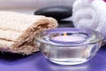 Spa Wellness Concept. Natural Loofah Sponge, rolled up White Towels, Basalt Stones, Orchid and burning Lavender Tea Light Candle Royalty Free Stock Photo