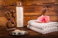 Spa or wellness set. White sea salt in white glass bottle, candle, towels, brown wooden statuette and pink flowers lily on brown Royalty Free Stock Photo