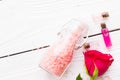 Spa and wellness setting with rose flower, sea salt, oil in a bottle on wooden white background Royalty Free Stock Photo