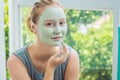 Spa Woman applying Facial green clay Mask. Beauty Treatments. Close-up portrait of beautiful girl applying facial mask Royalty Free Stock Photo
