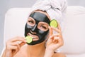 Woman with black charcoal facial mask and cucumber slices. Beauty treatments Royalty Free Stock Photo