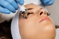 Spa worker makes lady face massage with appliance in office Royalty Free Stock Photo