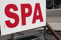 spa writing caption text sign signboard with road behind, red on white. p