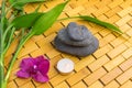 Spa, zen, massage concept. Bamboo leaves, black stones, purple orchid, candle on wood background Royalty Free Stock Photo