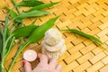 Spa, zen, massage concept. Woman hand holding lighting candle, bamboo leaves and white stone pyramid Royalty Free Stock Photo