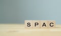 SPAC symbol. Wooden cubes with words SPAC, special purpose acquisition companies` on beautiful grey background, copy space. Inves