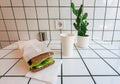 Space of hipster cafe with electricity, white tile wall and fast-food breakfast - coffee in paper and vegetables toast.