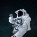 Space man in a suit with a helmet waves his hand and greeting in open space. Hello concept. Astronaut travels