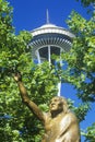 Space Needle with statue of Chief Seattle at base in Seattle, WA against blue sky