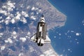 Space ship shuttle flying near earth from the hurricane and massive clouds in atmosphere, image made of NASA photos f