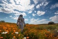 space traveler standing among field of wildflowers, with blue sky and clouds in the background