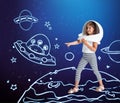 Contemporary artwork with little girl in huge white astronaut helmet standing among drawn planets, asteroids and stars