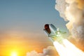 Spaceship lift off. Space shuttle with smoke and blast takes off into space on a background of sunset.