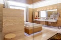 Spacious bathroom with marble walls and window complete with soaking bathtub