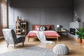 Spacious bedroom interior with pouf and gray armchair in front o Royalty Free Stock Photo