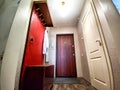 Spacious Hallway With Red Accent Wall, Wooden Doors, and Laminate Flooring. The hallway of an old poor Soviet apartment Royalty Free Stock Photo