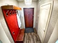 Spacious Hallway With Red Accent Wall, Wooden Doors, and Laminate Flooring. The hallway of an old poor Soviet apartment Royalty Free Stock Photo