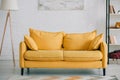 Spacious, light living room with bright yellow sofa, floor lamp