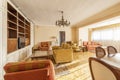 A spacious living room in a house with antique furniture with a yellow fabric lounge chair and other sofas, a white wooden Royalty Free Stock Photo