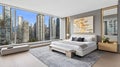 A spacious master bedroom showcases a large bed, navy blue accent wall, and a stunning view of the Toronto skyline