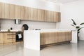 A spacious and modern kitchen interior with light wood cabinetry, white counters, and clean lines on a neutral background, Royalty Free Stock Photo