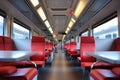 A spacious and modern train interior bathed in natural light, featuring rows of empty red seats facing each other with Royalty Free Stock Photo