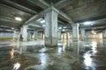 Spacious underground parking garage featuring concrete pillars and a wet flooring surface Royalty Free Stock Photo