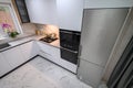 A spacious and updated kitchen with a white color scheme and marble floor