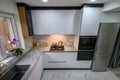 A spacious and updated kitchen with a white color scheme and marble floor