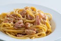 Spaghetti alla carbonara in a white soup plate with egg and guanciale. Italian cuisine