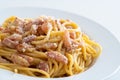 Spaghetti alla carbonara in a white soup plate with egg and guanciale. Italian cuisine