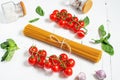 Spaghetti, basil and tomatoes isolated on white wooden table. Royalty Free Stock Photo