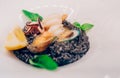 Spaghetti black rice with seafood in sause with lemon slice. spaghetti with scallops shells squid ink with prawns, mussels and par