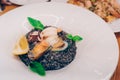 Spaghetti black rice with seafood in sause with lemon slice. spaghetti with scallops shells squid ink with prawns, mussels and par